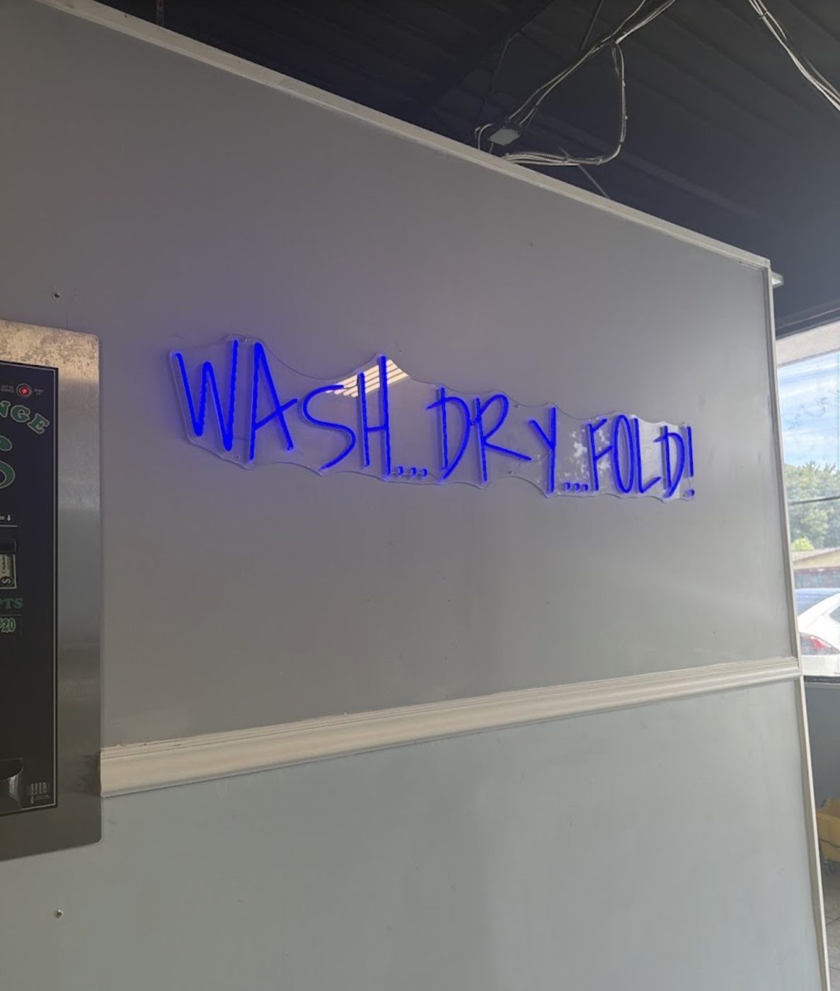 Blue neon sign reading Wash Dry Fold